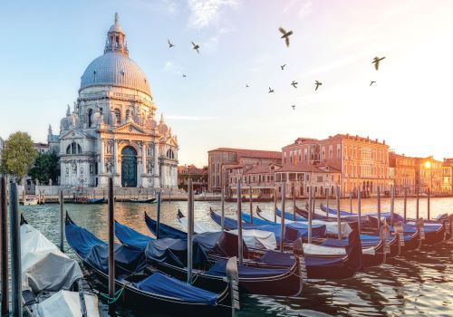 Early morning sunshine on gondolas parked in a canal in Venice with the Santa Maria Della Salute church in the background