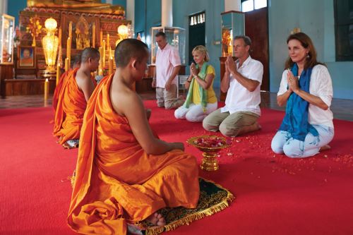 Cambodian monks dressed in bright orange robes blessing travellers in a ceremony