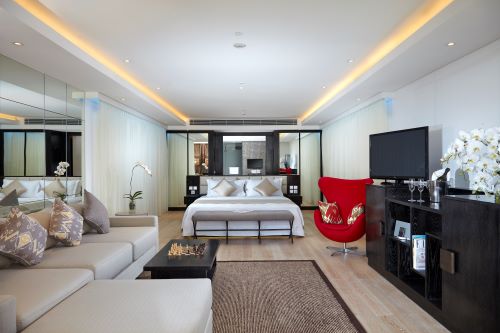A modernly furnished Leisure Suite with a big comfortable bed in the middle, an L-shaped couch and coffee table as well as TV and mini bar arrangements, 