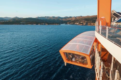 An orange mechanical structure on the side of a cruise ship