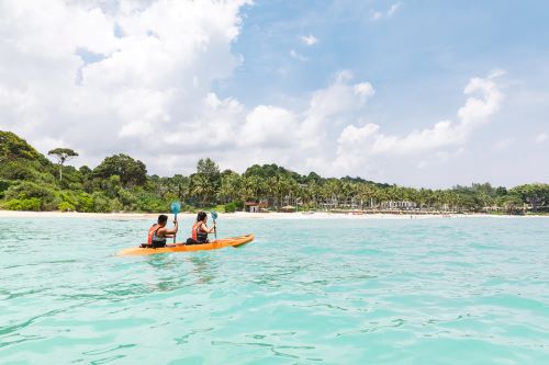 A couple on a kayak paddling through clear turquoise water 