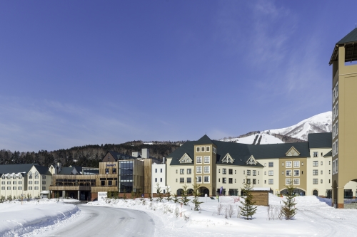The Tomamu resort from outside surrounded by snow against a bright blue sky