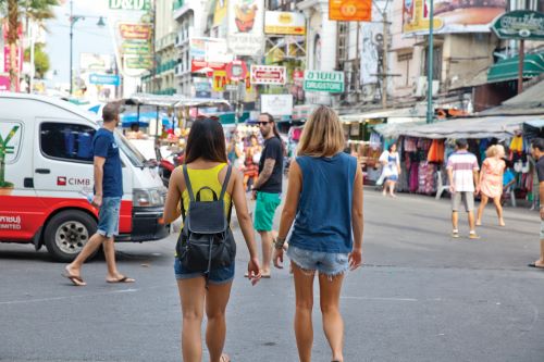 A couple of young travellers walking down a busy street in Asia