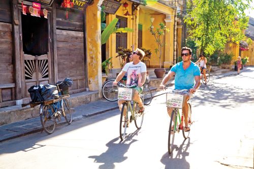 A couple of young travellers driving down the road on pushbikes in Asia 