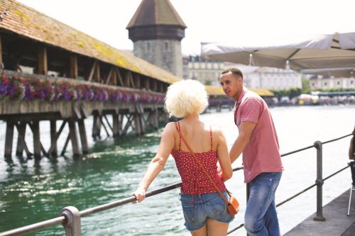 A couple of young travellers in front of the wooden covered Chapel Bridge in Lucerne 