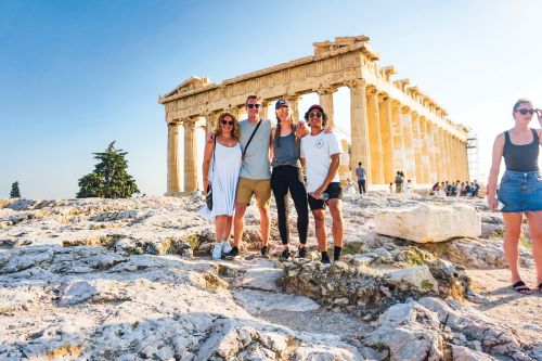 A group of young travellers posing for a photo in front of the acropolis in Athens 