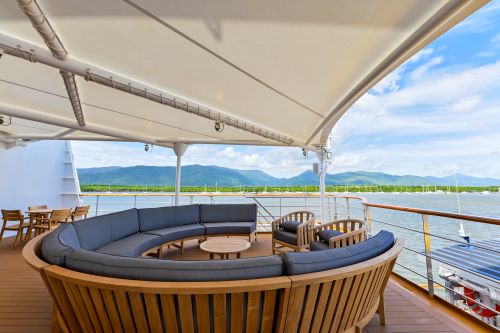 A sundeck at the back of the Coral Geographer vessel featuring seating arranged in a circle inviting passengers to talk to each other while enjoying the view