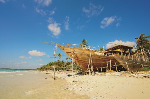 A wooden ship surrounded by traditional wood construction set on the beach