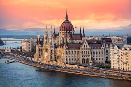 The majestic looking building of Hungarian Parliament on the Danube River at sunset