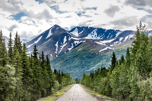 Train tracks leading down to a towering mountain landscape in Denali National Park