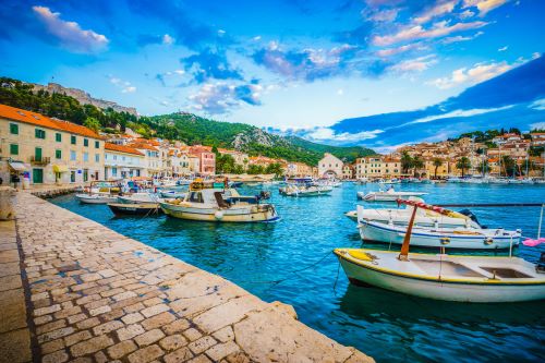 Small boats in the town of Hvar with mountains and buildings showing in the background 