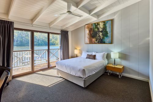 A sunny room with a cosy bed and a balcony overlooking the lake at RAC Karri Valley Resort