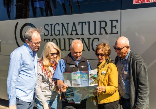 GPT tour guide standing in front of the coach and showing a map to travellers