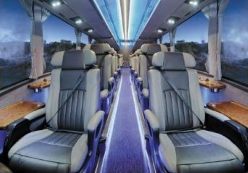 Interior of the Ultimate Coach with comfortable leather seats, all window seats with a side table for each passenger 
