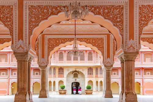 A symmetrical photo of the Jaipur City Palace and its magnificent blend of vibrant pink and cream facades and intricately carved doorways