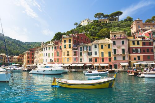 View of beautiful fisher town Portofino with colourful houses along the small harbour and green hills in the background. 