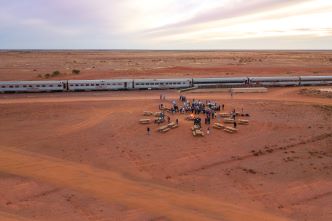 Travellers having canapes in the middle of the outback by the fire in front of the iconic Ghan