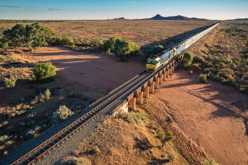 The Indian Pacific heading east towards Broken Hill Pinnacles mountains in background