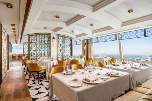 A restaurant setting with tables and chairs with bright decor onboard an Oceania cruise ship