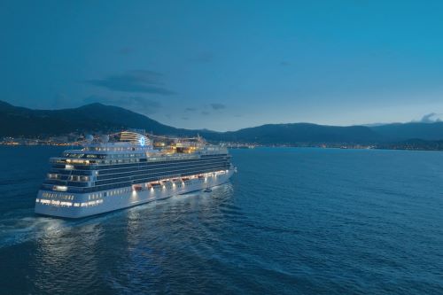 A cruise ship sailing on the Oceania with Santorini in the background at dusk