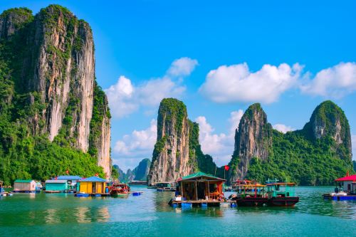 Vietnamese water village with the towering cliffs of Ha Long Bay in the background