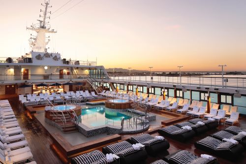 Pool deck with lots of sun lounges and two hot tubs next to the pool