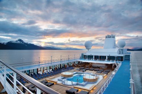 View of the pool deck with sun lounges and day beds surrounding a pool and two hot tubs