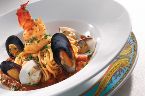 A close up of Cioppino a fish stew with pasta, seafood and red sauce served in a white plate