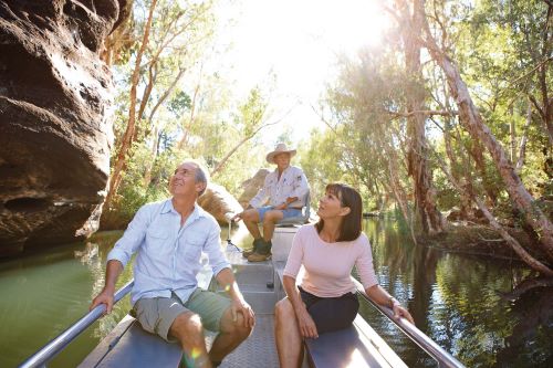 A couple is sitting in a little boat with a local guide steering through the river