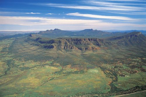 An aerial view of Wilpena Pound, a rock formation of a natural amphitheatre surrounded by green bushland 