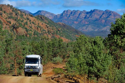 The Outback Spirit Mercedes Benz 4WD coach driving through rock formations and bushland surrounded by the outback of the Flinders Ranges