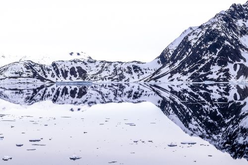 A glacier in Greenland with the iceburgs reflectin on the still water