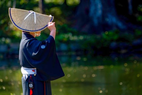 A person dressed in a traditional japanese Kimono and a bamboo kasa 