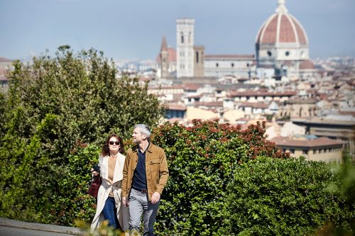 A couple is walking up a hill with the city view of Florence in the background