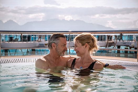 A couple sitting in a whirlpool aboard the cruise ship and smiling at each other