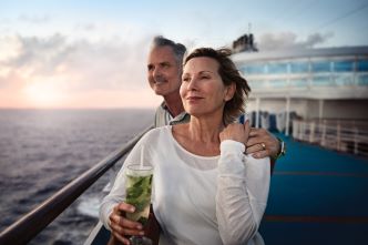 A happy couple standing on deck and looking out to the ocean