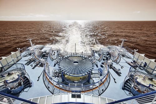 Back deck of a cruise ship with a three spas and tourists enjoying the sunshine