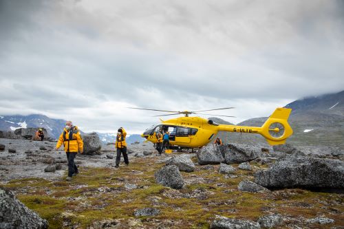 The bright yellow Quark Expeditions helicopter letting out passengers on a heli hike
