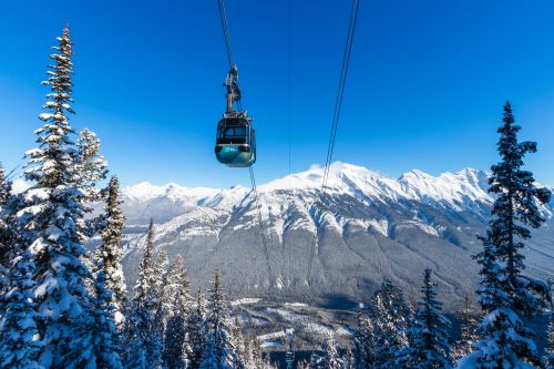 A cable car above snowy Canadian mountains and trees