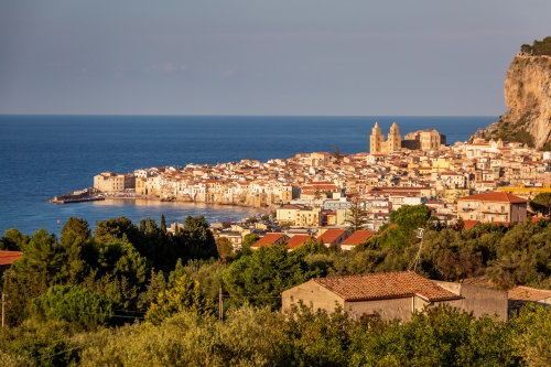 The vibrant coastal city of Catania at sunset stretching out into the blue sea. 