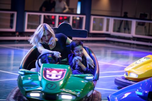 A woman with a boy sitting in a bumper car enjoying themselves.