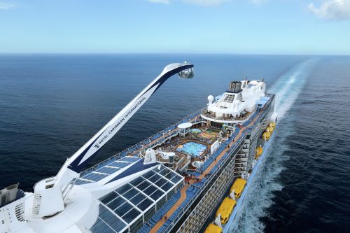 Aerial shot of a cruise ship showing the top deck with a pool and a glass capsule overlooking the ship