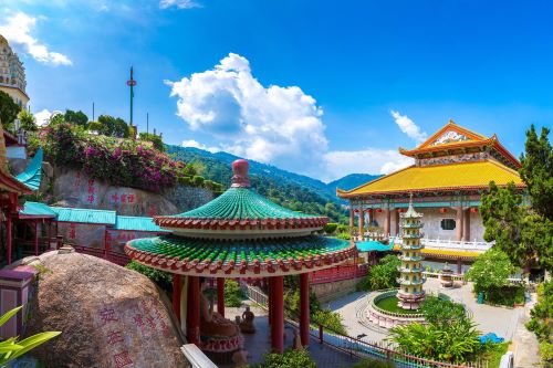 A vibrant temple complex in Penang with traditional Chinese architecture, including pagodas, colourful tiled roofs, and lush gardens.