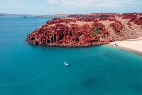 The deep red earth of the Dampier Archipelago against clear turquoise water 