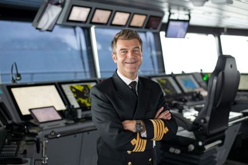 Captain of the Scenic Eclipse 2 posing inside the vessel's bridge and smiling