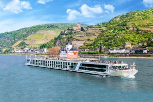 Scenic river vessel sailing along the Rhine River with a green hilly landscape in the background. 
