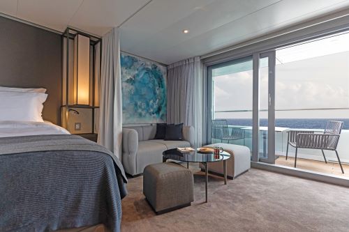 Stateroom on the Scenic Eclipse ship with with a bed and sitting area and a veranda with a table setting