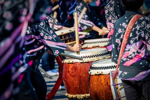 Close up of people wearing traditional Japanese robes and playing Japanese drums 