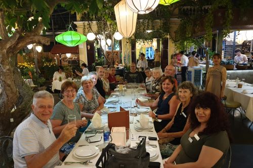 A group of happy travellers sitting at a long table in a local Cambodian restaurant 