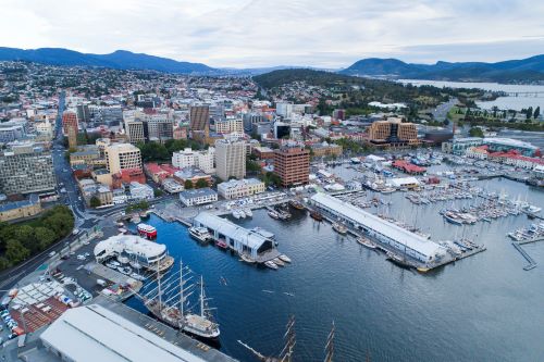 An aerial view of Hobart's waterfront with the harbour full of boats and the blue mountains in the back